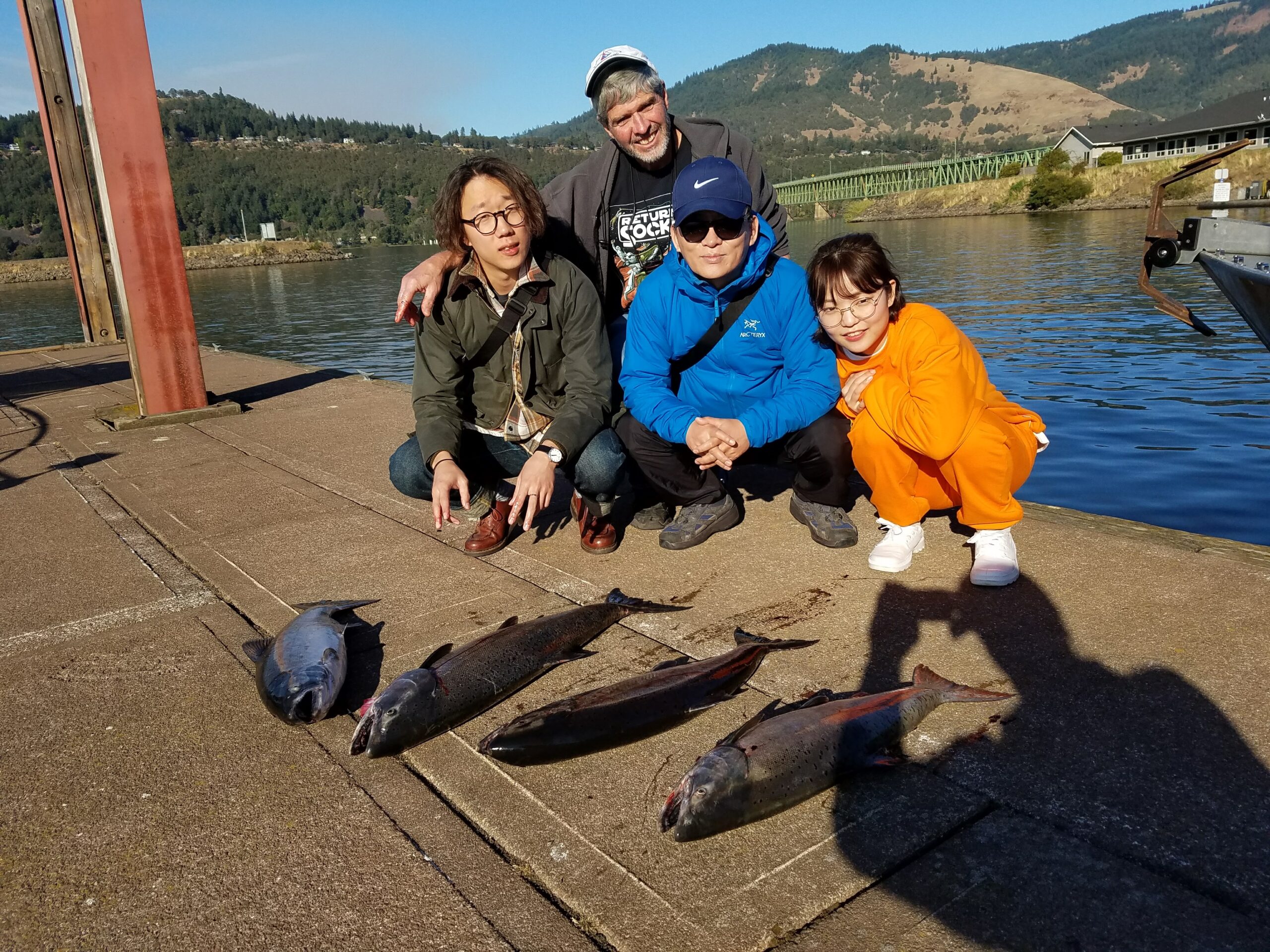 Family kneeling on dock with 4 salmon