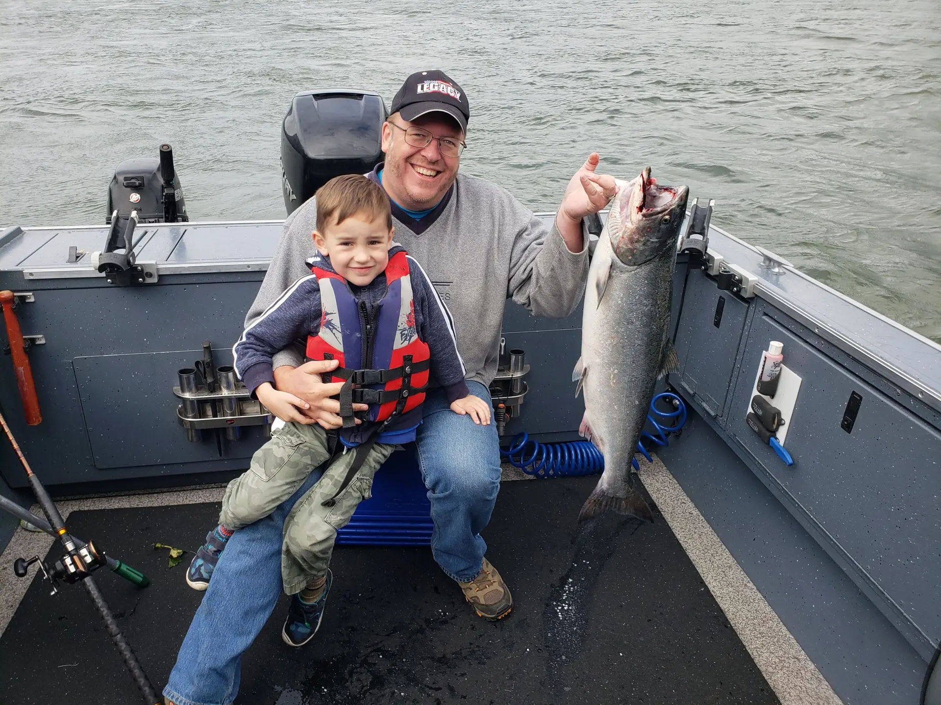 Dad holding small child and salmon in other hand