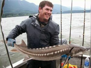 Jess Zerfing the owner in rain gear holding a sturgeon