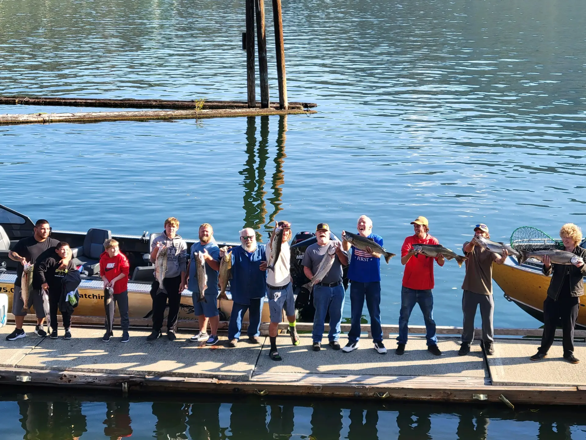12 people holding 12 Fall Chinook Salmon on a dock in the morning after limiting
